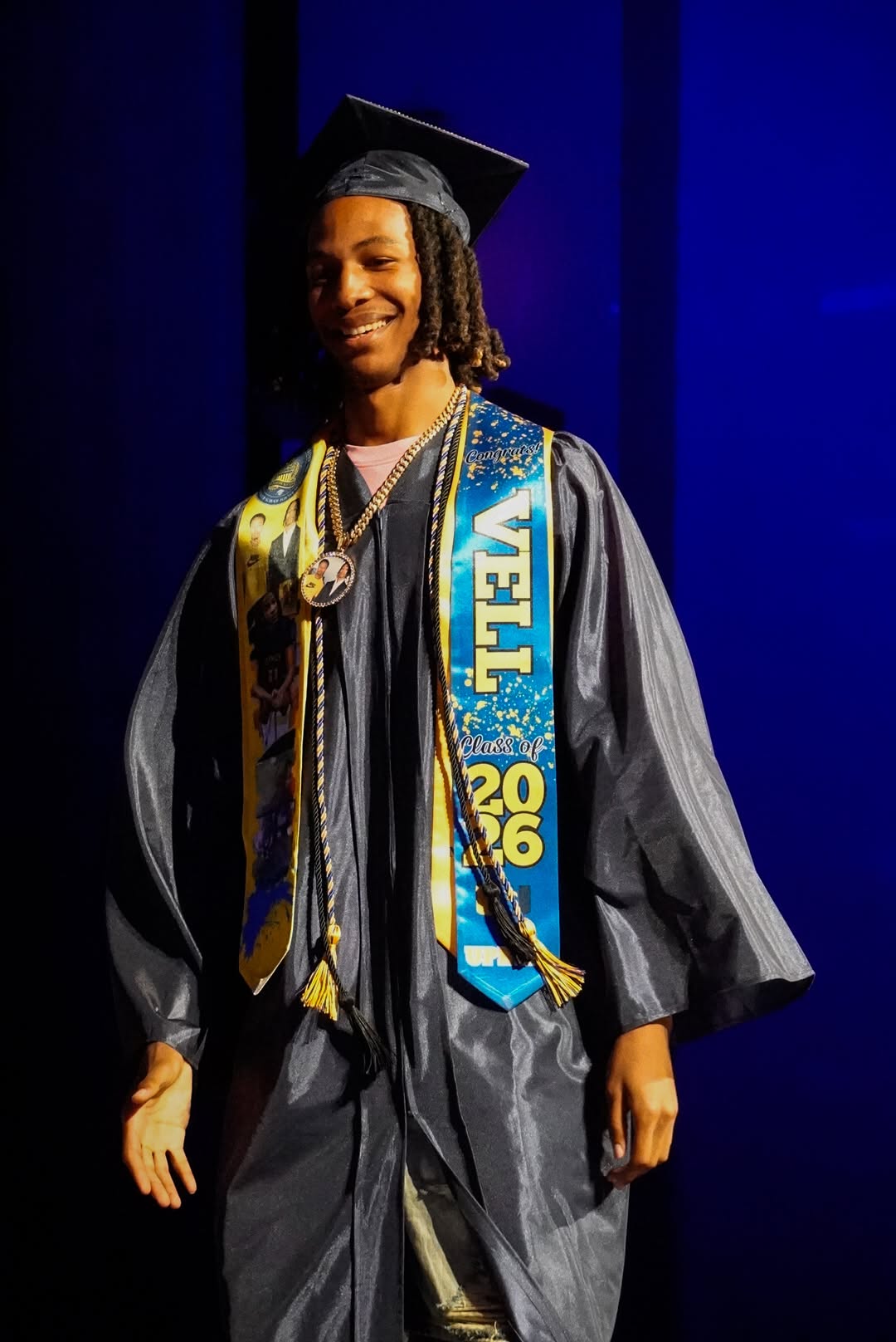 A UPrep graduate in a blue and gold stole smiling on stage