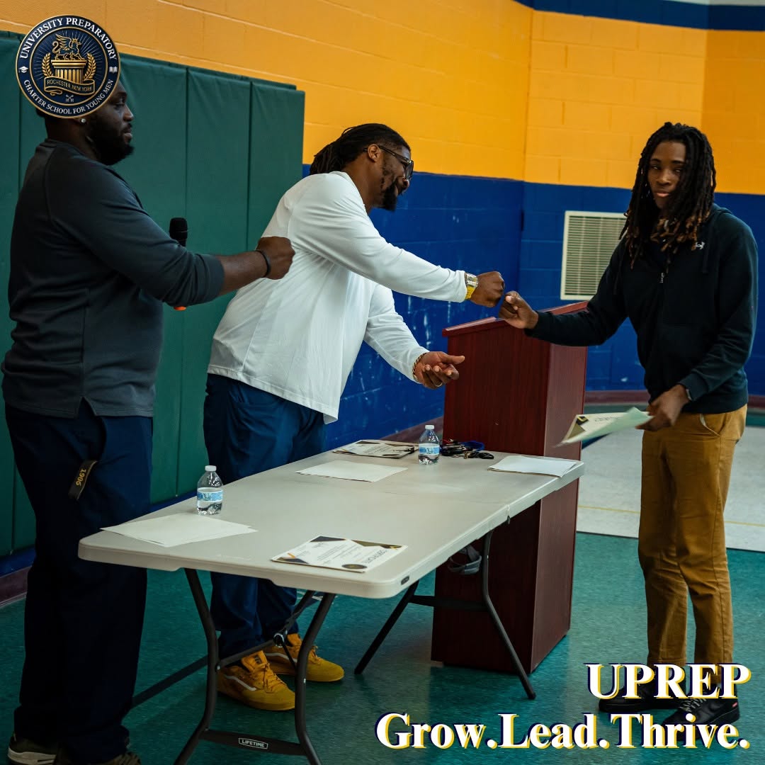 A fist bump at a UPrep awards podium beneath a Grow Lead Thrive banner