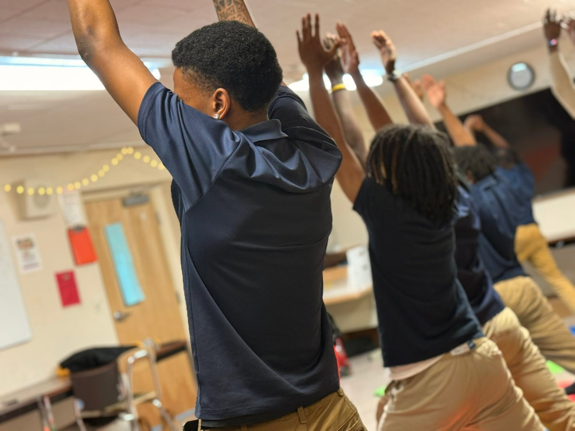 UPrep students standing in a classroom circle with their arms raised
