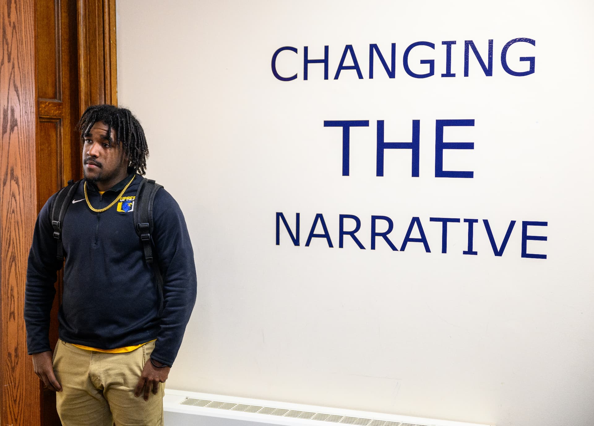 A UPrep student standing beside a wall reading Changing The Narrative