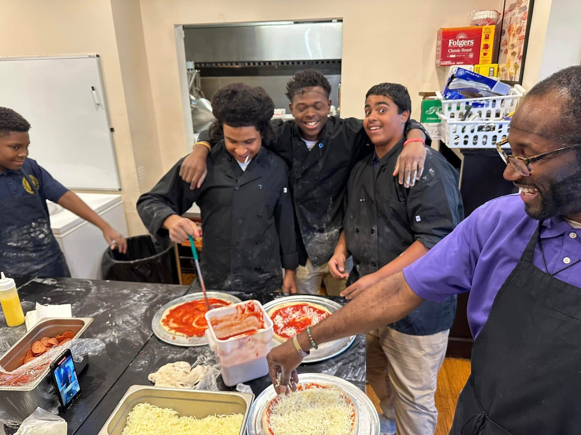 UPrep culinary students laughing together while making pizzas in the kitchen