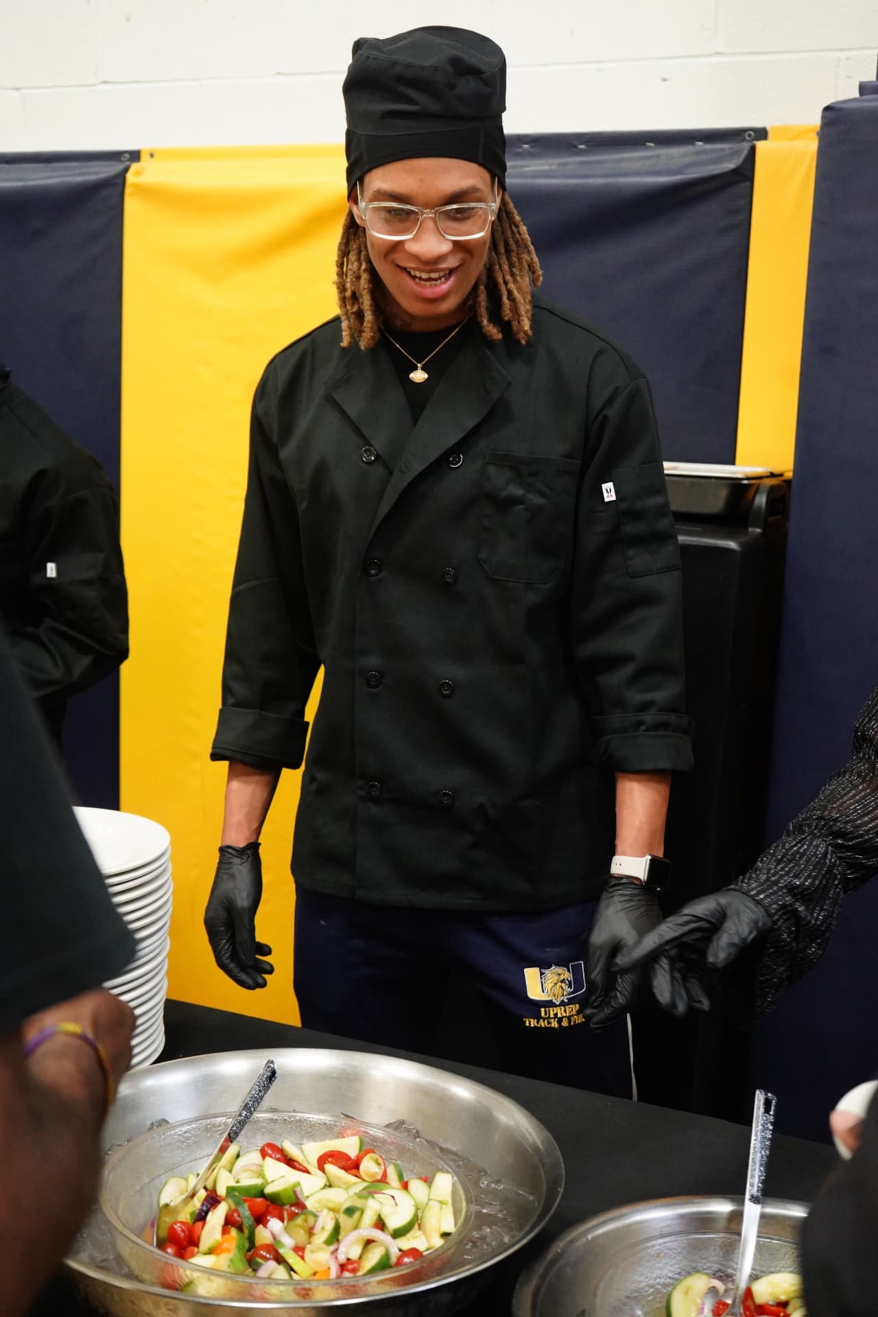A UPrep culinary student in chef's coat serving food at a school event